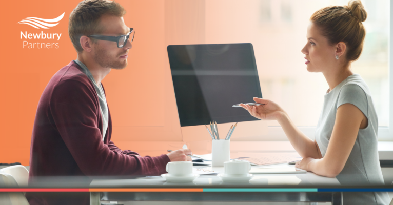 A man and a woman sitting at a table with a computer.