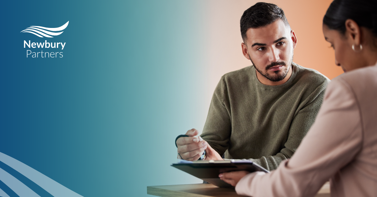 A man and woman at a table discussing high-volume hiring compliance.