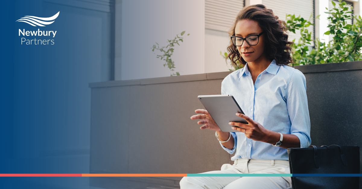 A woman sitting on a bench using a tablet.