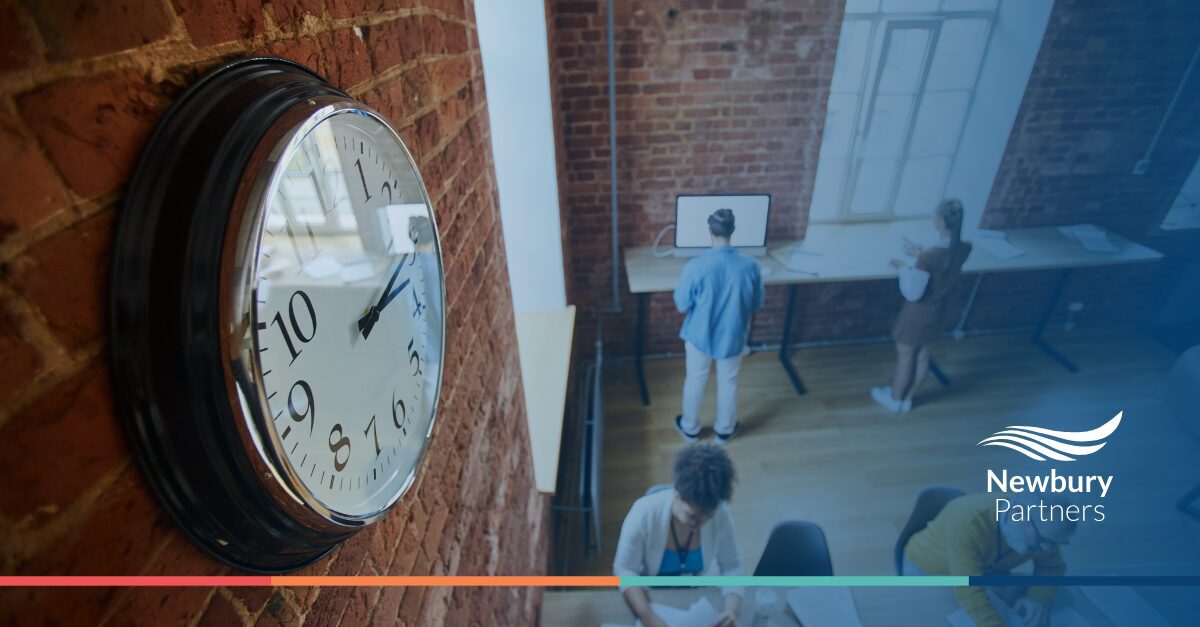 A wall clock in a room where people are seated, symbolizing time spent on recruitment system integration and workflow automation.